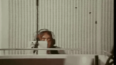 A Woman Is Sitting At A Desk In Front Of A Microphone . GIF