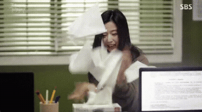 A Woman Is Sitting At A Desk With A Box Of Tissues In Front Of A Computer . GIF
