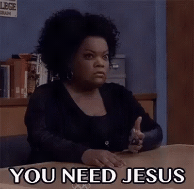 A Woman Is Sitting At A Desk With A Gun In Her Hand And The Words `` You Need Jesus '' Written On Her Face . GIF