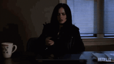 A Woman Is Sitting At A Desk With A Laptop And A Cup Of Coffee And A Netflix Logo In The Corner . GIF