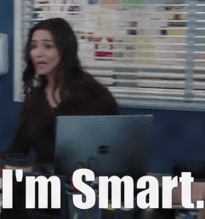 A Woman Is Sitting At A Desk With A Laptop And The Words I 'M Smart Behind Her GIF