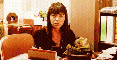 A Woman Is Sitting At A Desk With A Potted Plant On It . GIF
