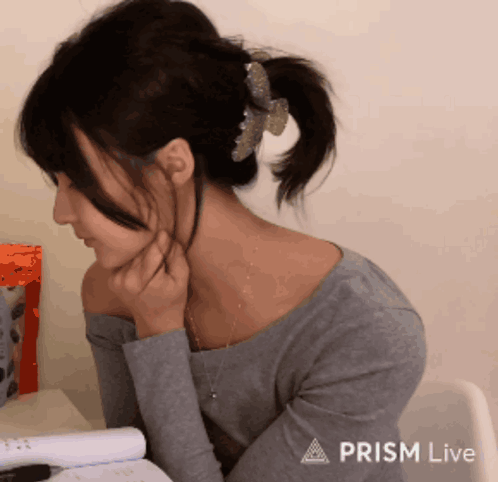 A Woman Is Sitting At A Desk With A Prism Live Logo On The Bottom GIF