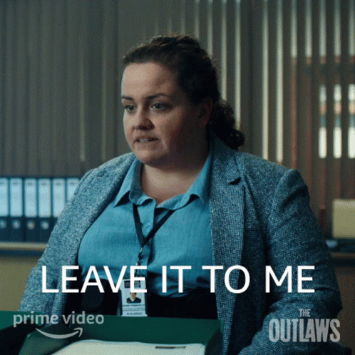 A Woman Is Sitting At A Desk With The Words " Leave It To Me " On The Screen GIF