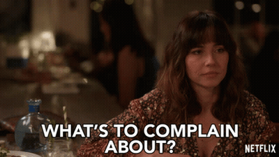 A Woman Is Sitting At A Table And Says What 'S To Complain About Netflix GIF
