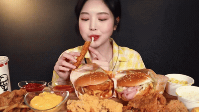 A Woman Is Sitting At A Table Eating A Bunch Of Fried Food . GIF