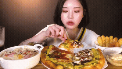 A Woman Is Sitting At A Table Eating A Pizza . GIF