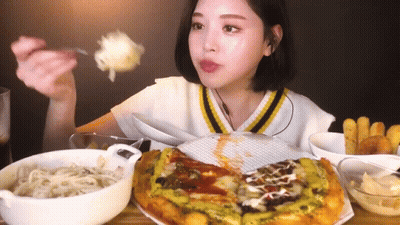 A Woman Is Sitting At A Table Eating A Pizza With A Fork And Spoon . GIF