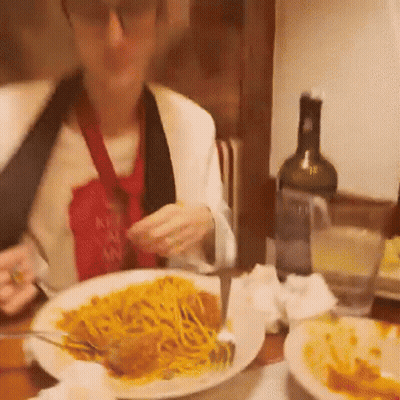 A Woman Is Sitting At A Table Eating A Plate Of Spaghetti With A Knife And Fork . GIF