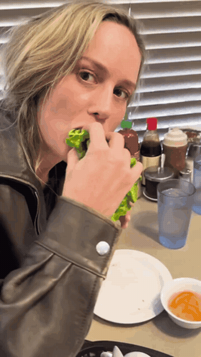 A Woman Is Sitting At A Table Eating A Salad GIF