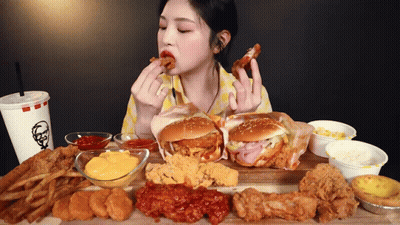 A Woman Is Sitting At A Table Eating A Variety Of Fried Food Including A Kfc Drink GIF