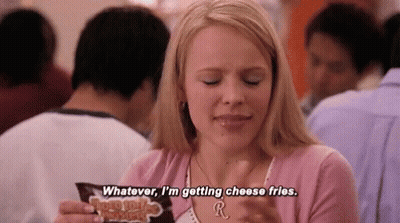 A Woman Is Sitting At A Table Eating Cheese Fries In A Restaurant . GIF