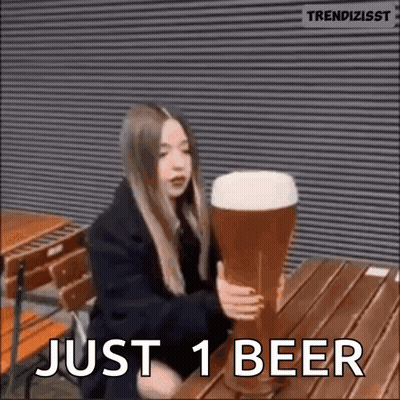 A Woman Is Sitting At A Table Holding A Giant Beer Glass . GIF