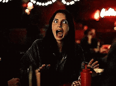 A Woman Is Sitting At A Table In A Dark Room With A Ketchup Bottle . GIF