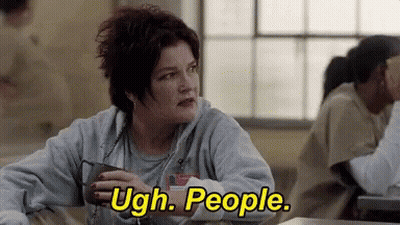 A Woman Is Sitting At A Table In A Prison Cell Holding A Cup Of Coffee And Saying Ugh . People . GIF