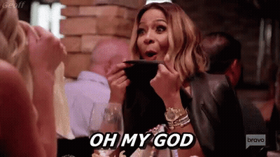 A Woman Is Sitting At A Table In A Restaurant Holding A Plate And Saying Oh My God . GIF