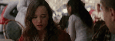 A Woman Is Sitting At A Table In A Restaurant With Her Eyes Closed And A Man Is Standing Behind Her . GIF
