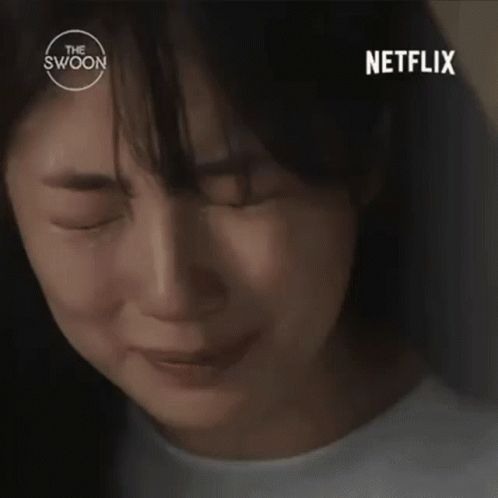A Woman Is Sitting At A Table In Front Of A Bookshelf And A Netflix Logo . GIF