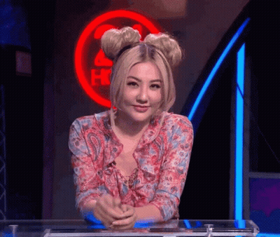 A Woman Is Sitting At A Table In Front Of A Sign That Says ' Hot ' GIF