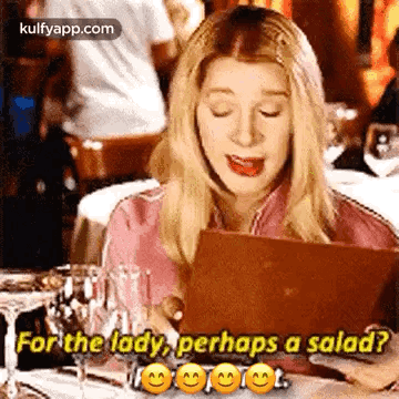 A Woman Is Sitting At A Table Looking At A Menu And Asking For A Salad . GIF