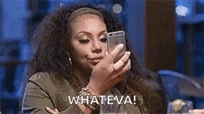 A Woman Is Sitting At A Table Looking At Her Cell Phone And Saying Whateva . GIF
