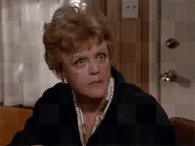 A Woman Is Sitting At A Table Making A Funny Face And Looking At The Camera . GIF
