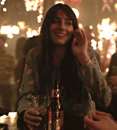 A Woman Is Sitting At A Table With A Bottle Of Coke GIF