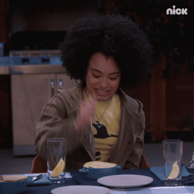 A Woman Is Sitting At A Table With A Bowl Of Food And A Nick Logo On The Bottom GIF