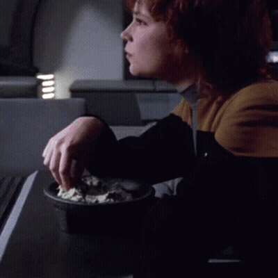 A Woman Is Sitting At A Table With A Bowl Of Food GIF