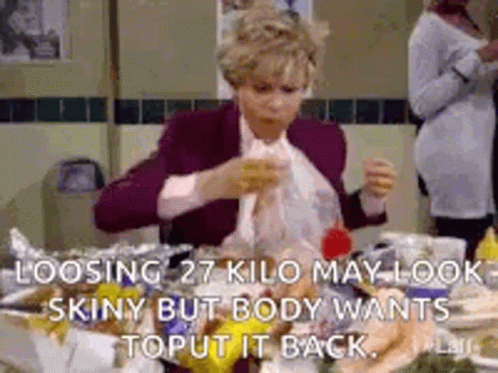 A Woman Is Sitting At A Table With A Bunch Of Food And A Bag Of Food . GIF