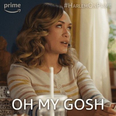 A Woman Is Sitting At A Table With A Drink In Her Hand And The Words Oh My Gosh On The Bottom GIF