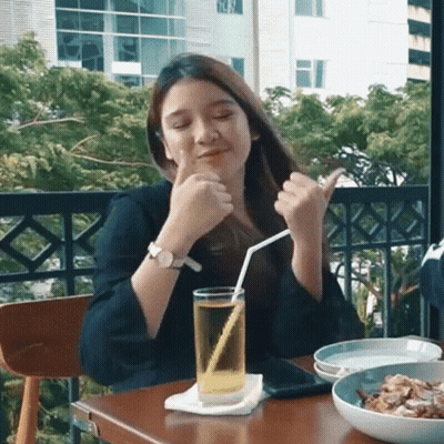 A Woman Is Sitting At A Table With A Glass Of Beer And A Straw . GIF