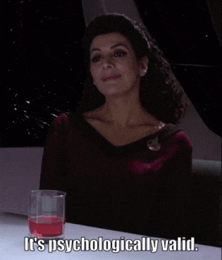 A Woman Is Sitting At A Table With A Glass Of Red Liquid And The Words It 'S Psychologically Valid GIF