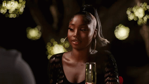 A Woman Is Sitting At A Table With A Glass Of Wine And It 'S 2 On The Bottom Right GIF