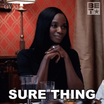 A Woman Is Sitting At A Table With A Glass Of Wine And Says Sure Thing GIF