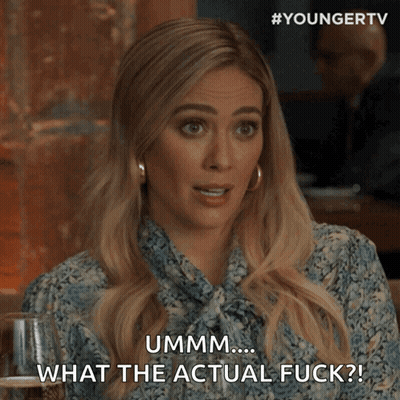 A Woman Is Sitting At A Table With A Glass Of Wine And Says " Ummm What The Actual Fuck " GIF