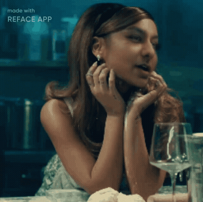 A Woman Is Sitting At A Table With A Glass Of Wine In Front Of Her And The Words Made With Reface App Below Her GIF