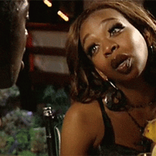 A Woman Is Sitting At A Table With A Man Looking At Her GIF