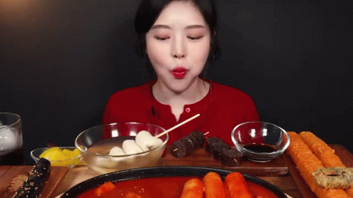 A Woman Is Sitting At A Table With A Plate Of Food And A Bowl Of Dipping Sauce . GIF