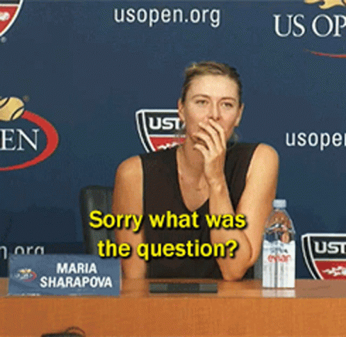A Woman Is Sitting At A Table With A Sign That Says Maria Sharapova GIF