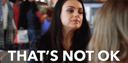 A Woman Is Sitting At A Table With A Sign That Says `` That 'S Not Ok '' GIF