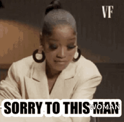 A Woman Is Sitting At A Table With A Sticker That Says `` Sorry To This Woman '' On It . GIF