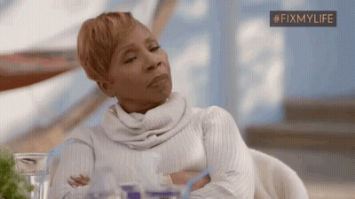 A Woman Is Sitting At A Table With Her Arms Crossed And Looking At Something . GIF