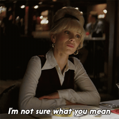 A Woman Is Sitting At A Table With Her Arms Crossed And Says I 'M Not Sure What You Mean GIF