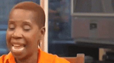 A Woman Is Sitting At A Table With Her Eyes Closed And Laughing . GIF