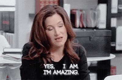 A Woman Is Sitting At A Table With Her Eyes Closed And Saying Yes , I Am I 'M Amazing . GIF