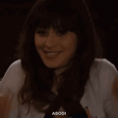 A Woman Is Sitting At A Table With Her Hand On Her Face And Smiling . GIF