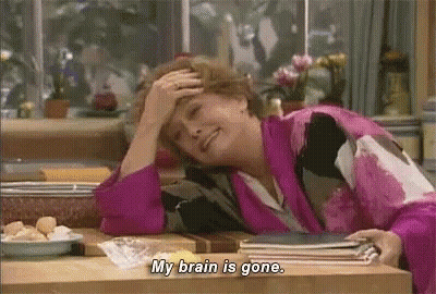 A Woman Is Sitting At A Table With Her Hand On Her Forehead And Saying `` My Brain Is Gone . '' GIF