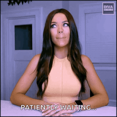 A Woman Is Sitting At A Table With The Words Patiently Waiting On The Screen GIF