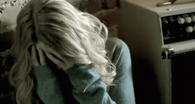 A Woman Is Sitting Down With Her Head In Her Hands . GIF